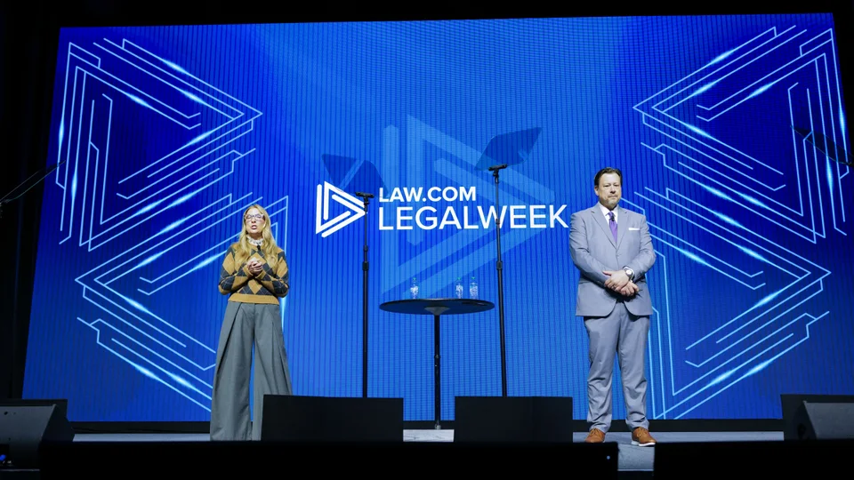 Presenters on the blue-lit Legalweek stage
